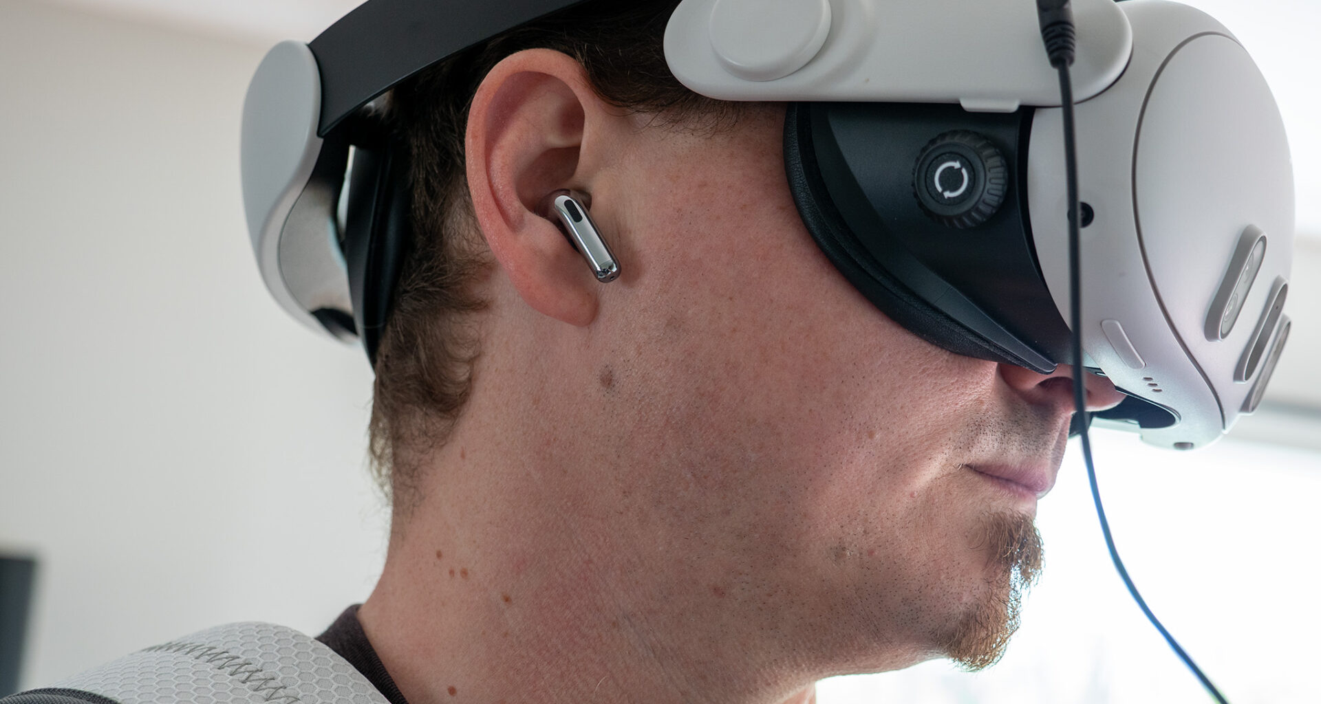 A Meta Quest 3 hooked up to a Woojer Haptic Vest 3 while wearing OnePlus Buds 3