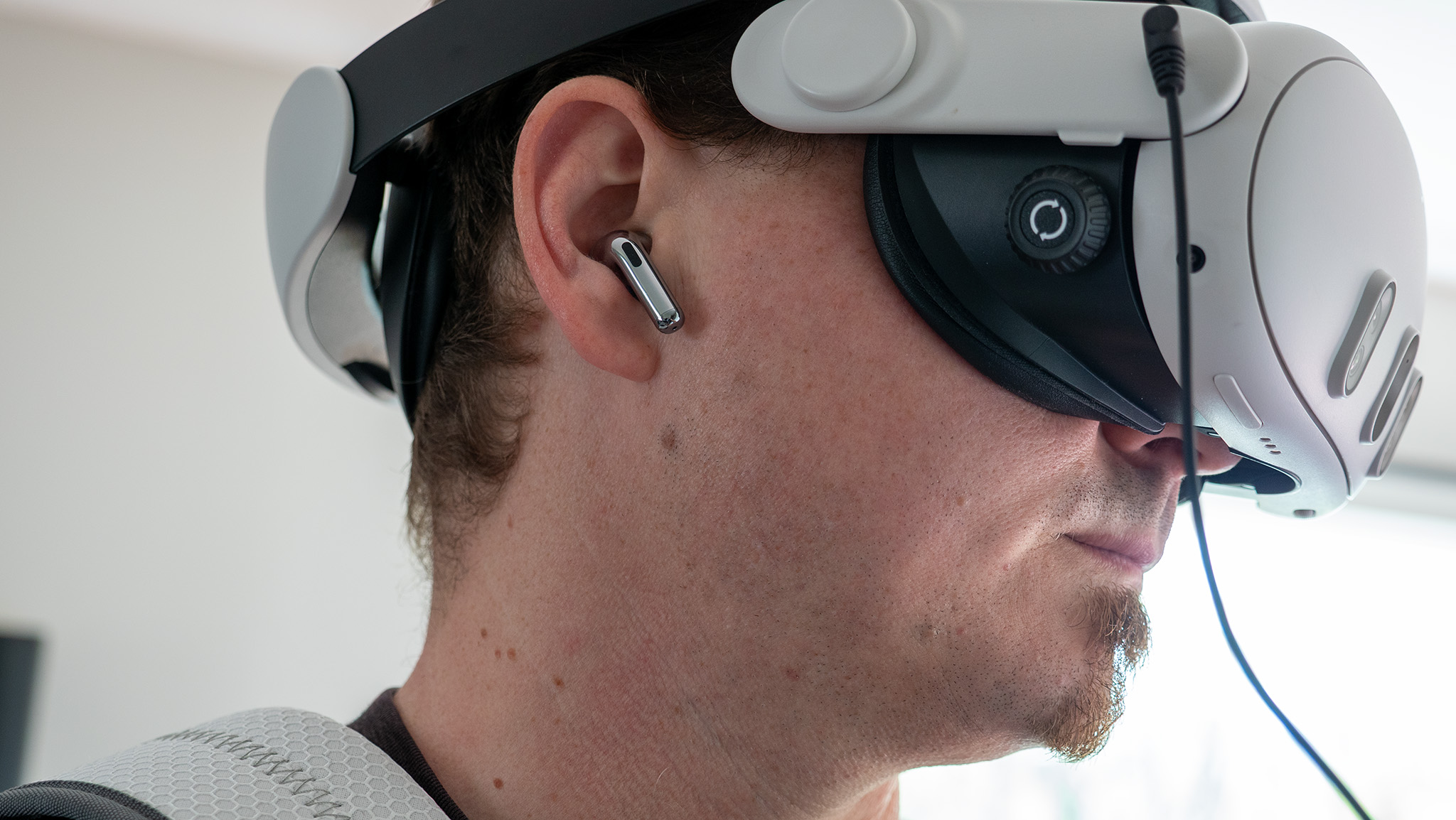 A Meta Quest 3 hooked up to a Woojer Haptic Vest 3 while wearing OnePlus Buds 3