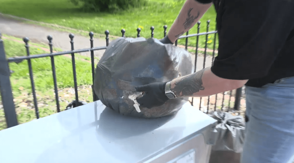 A rat catcher inspecting a large bag of rubbish.