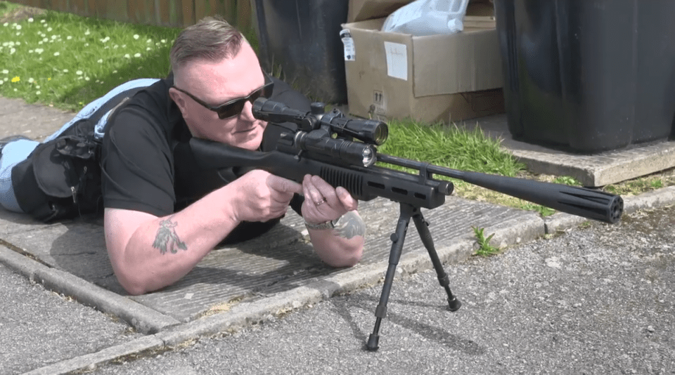 A man aiming a rifle at rats.