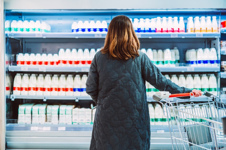 Woman shopping for milk in a supermarket.