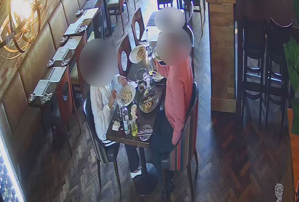CCTV footage of a couple at a restaurant table; their faces are blurred.