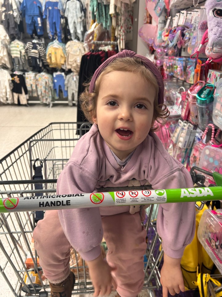 Toddler sitting in a shopping cart.