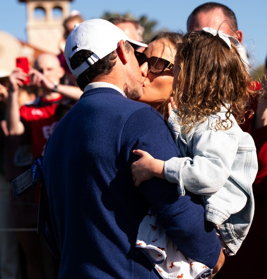Rory McIlroy kissing his wife while holding their daughter.