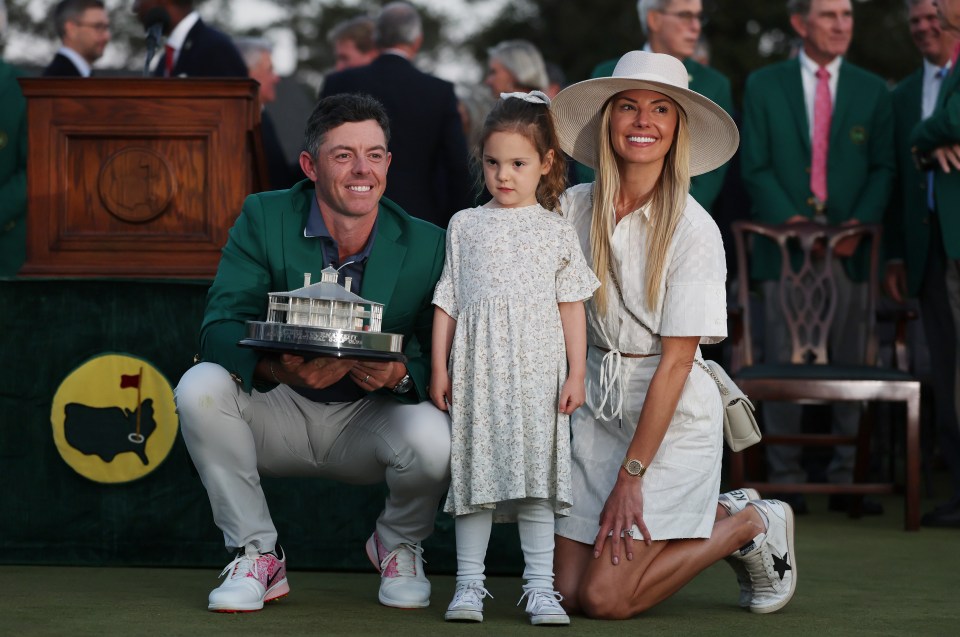 Rory McIlroy with his wife and daughter, holding the Masters trophy.