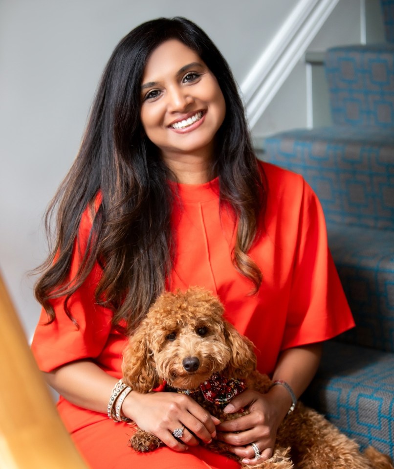 Woman in orange dress holding a small brown dog.