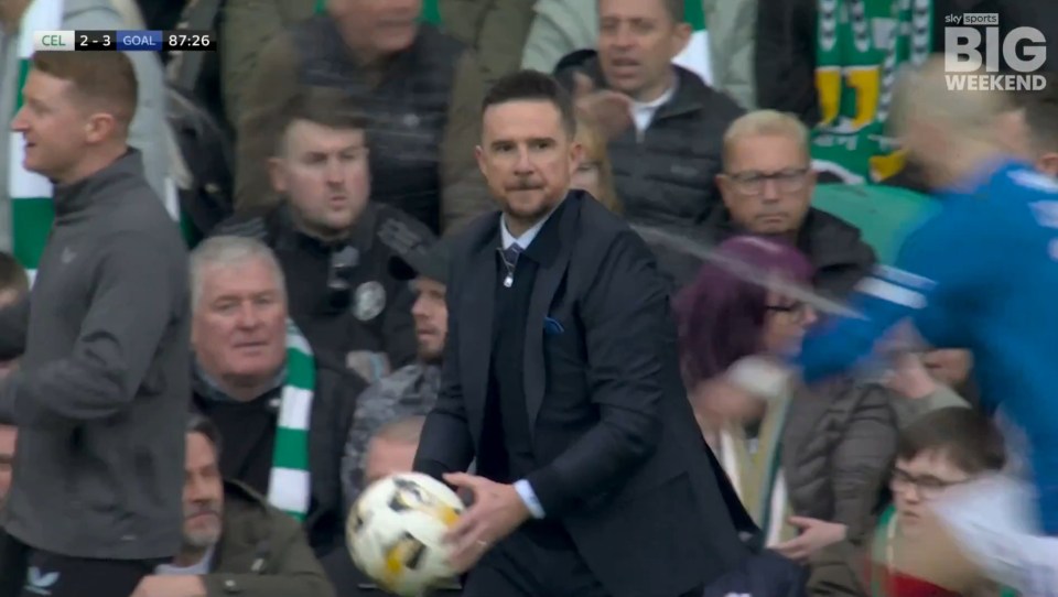 Screengrab of a man in a suit holding a soccer ball at a Celtic v Rangers game.