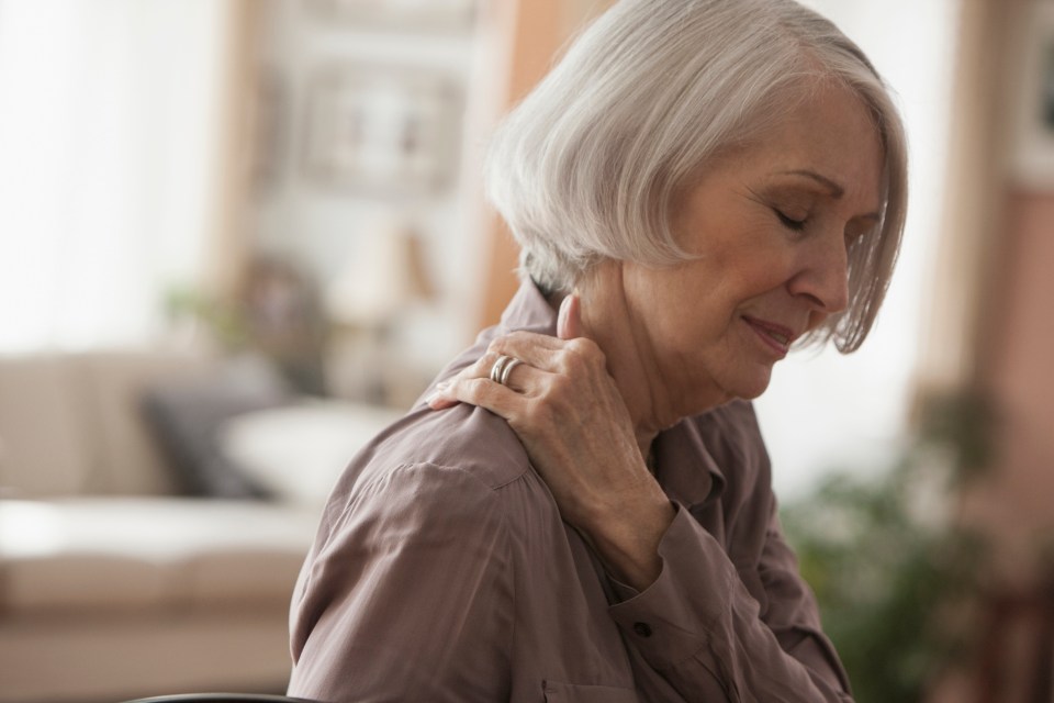 Senior woman holding her shoulder.
