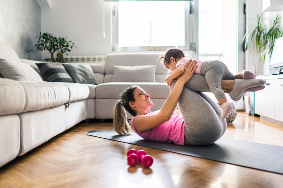 A mother exercising at home with her baby.