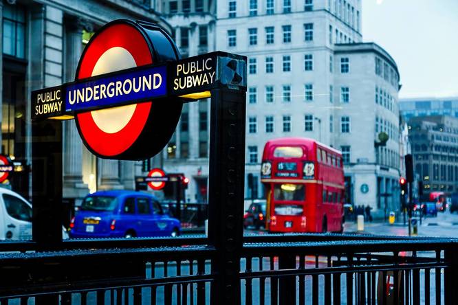 An image of a sign outside a London underground station with a red bus in the background