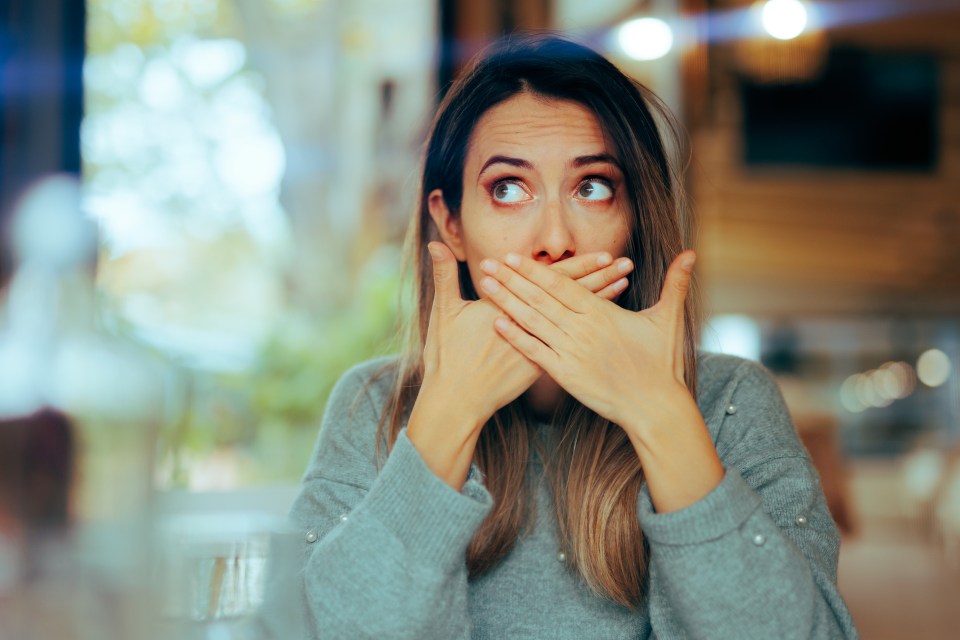 Woman covering her mouth, looking nauseous.