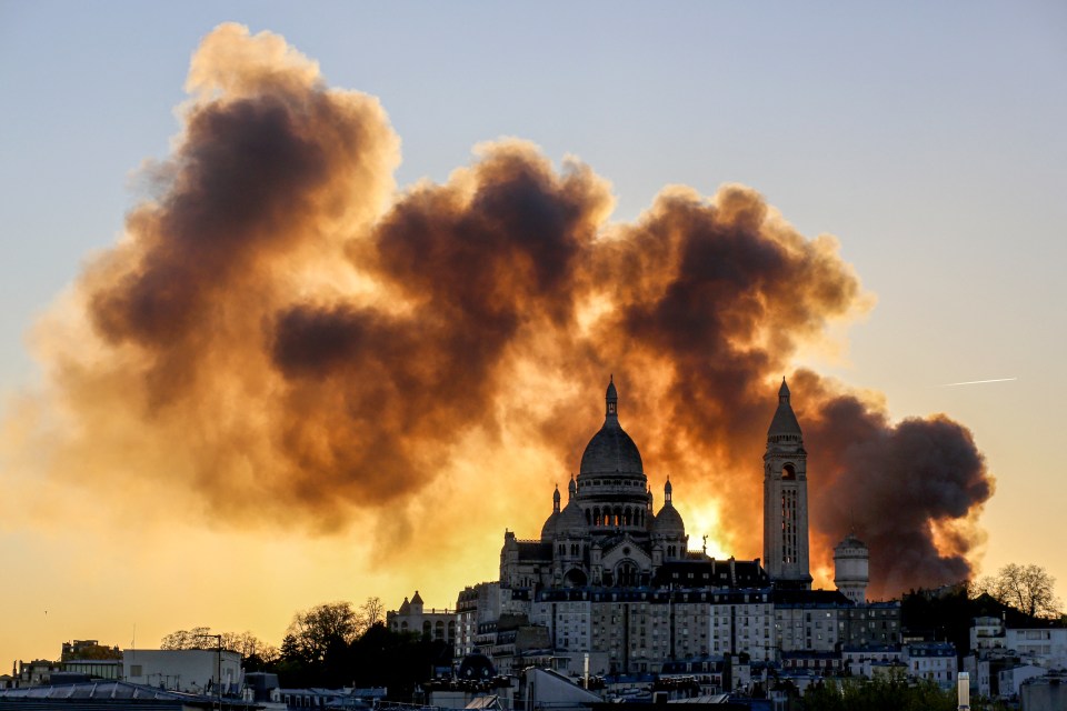 Smoke from a large fire billows behind the Sacré-Cœur Basilica in Paris.