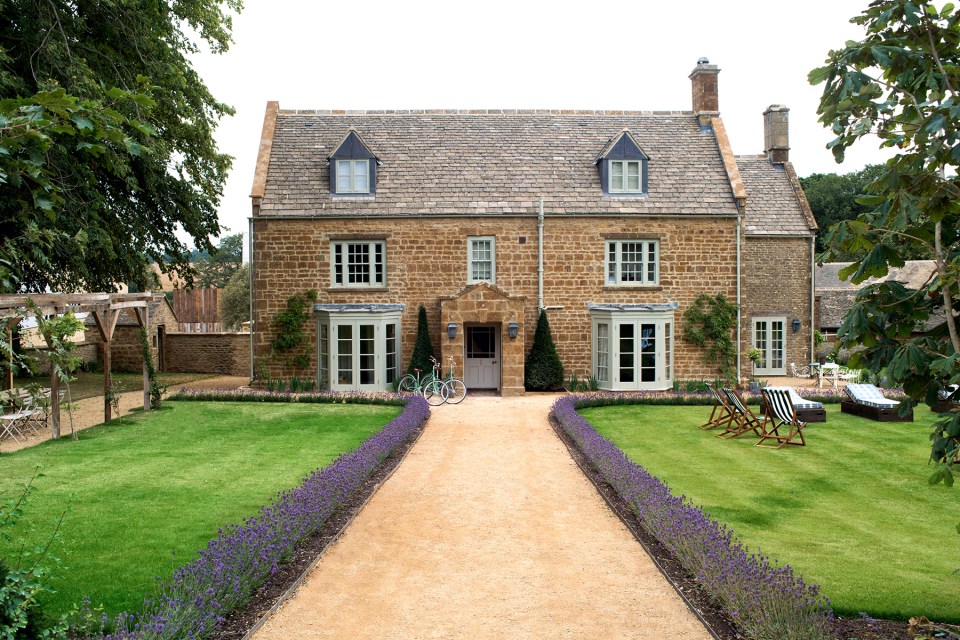 Stone farmhouse with lavender lined pathway and outdoor seating.