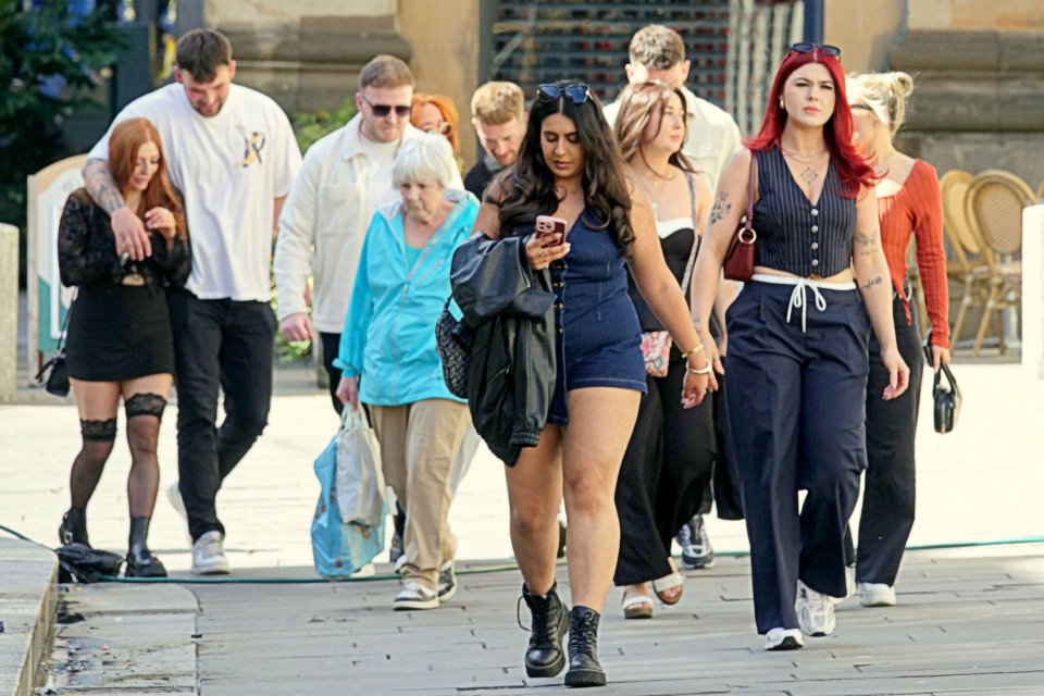 People walking down a city street on a sunny day.