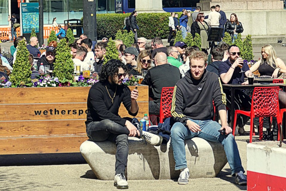 People enjoying sunny weather at an outdoor cafe in Glasgow, Scotland.