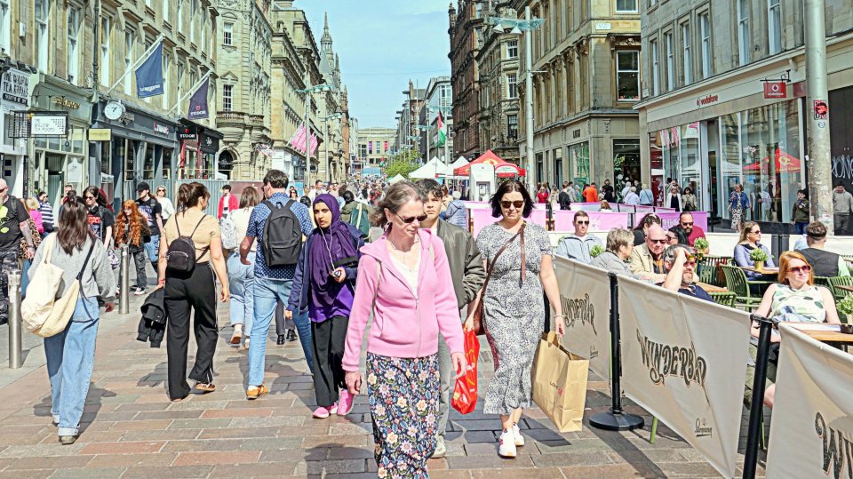 Crowds of people walking down a sunny city street.