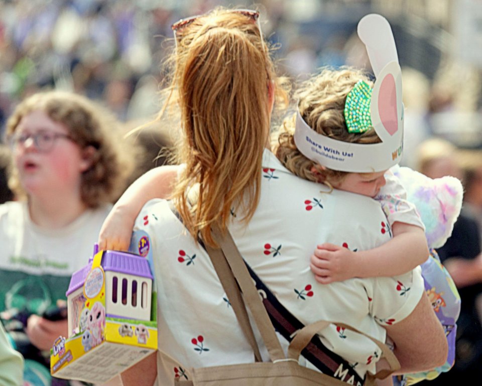 Woman carrying a child in a crowd.