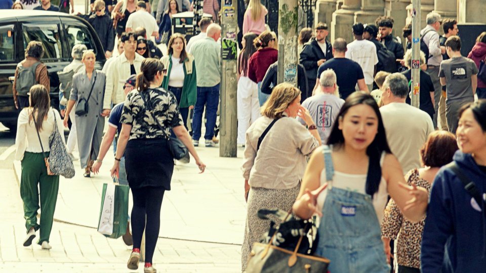 Crowds of people walking in a city street.