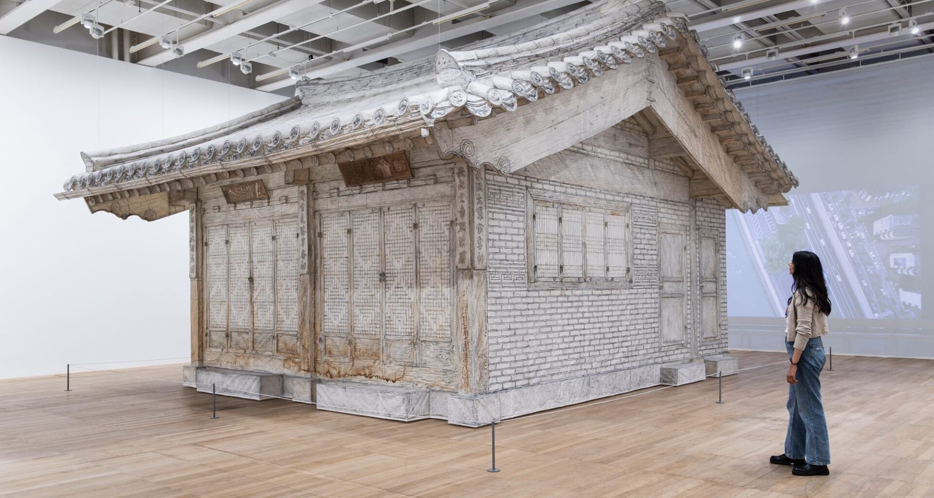 a life-size installation of a traditional Korean home made of white fabric in a gallery space