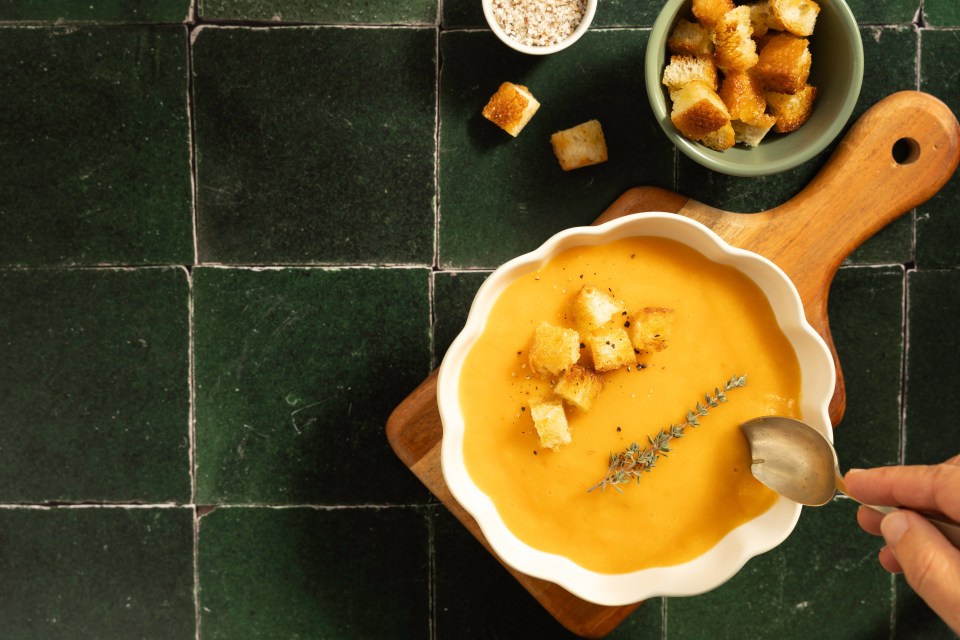 Creamy pumpkin soup garnished with thyme and croutons.