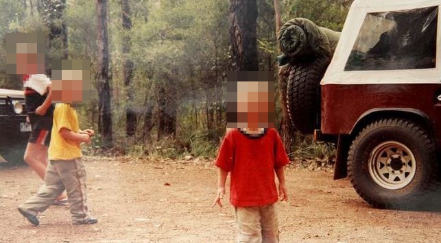 Photo of children near a vehicle in a wooded area; faces blurred.