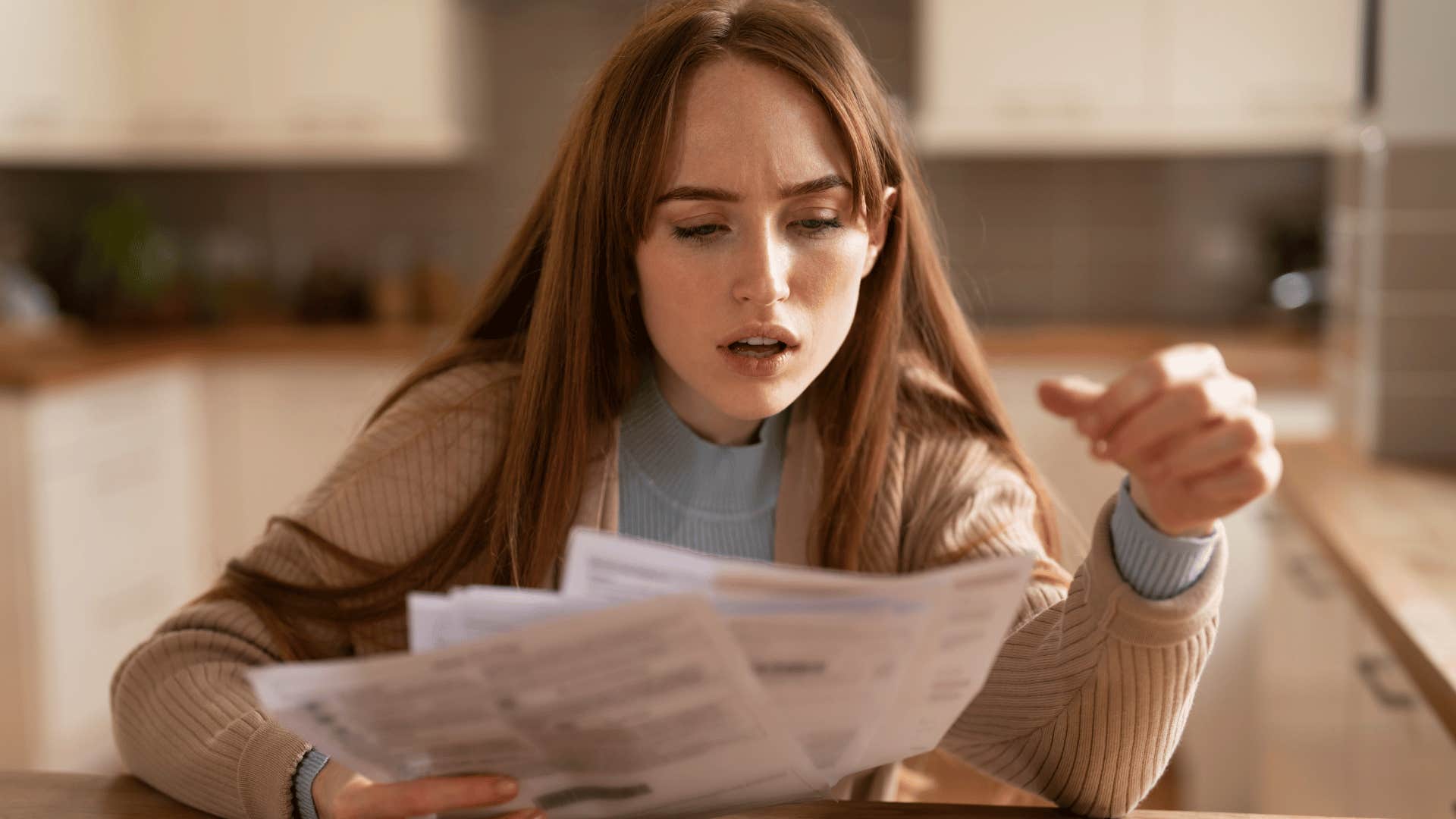 shocked woman looking at bills with her loans and interest payments on them