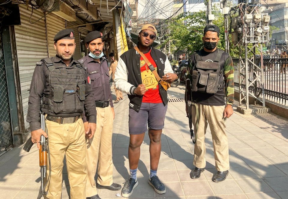A man stands between two armed police officers on a city street.