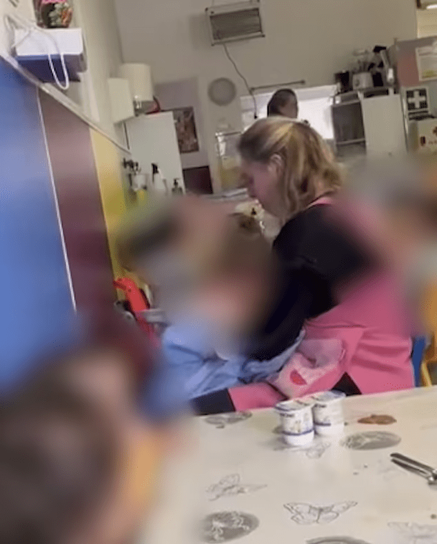 Blurred image of a nursery worker with a child; the child's face is obscured.