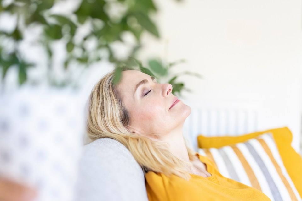 Woman relaxing on a couch with eyes closed.