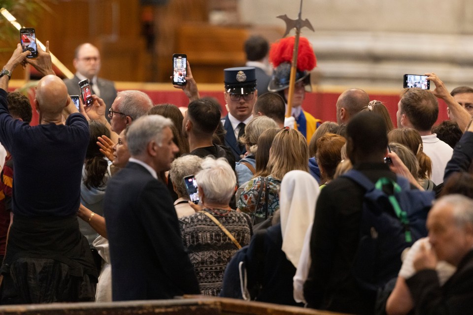 People taking photos of Pope Francis' body lying in state at St. Peter's Basilica.