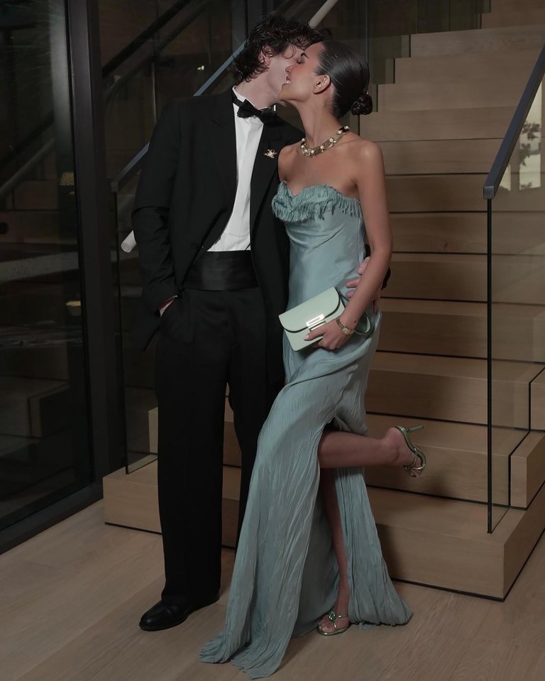 Couple kissing on a staircase; the woman is wearing a light blue gown.