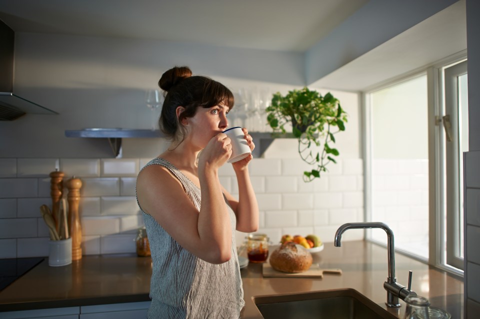Woman drinking from a mug in her kitchen.