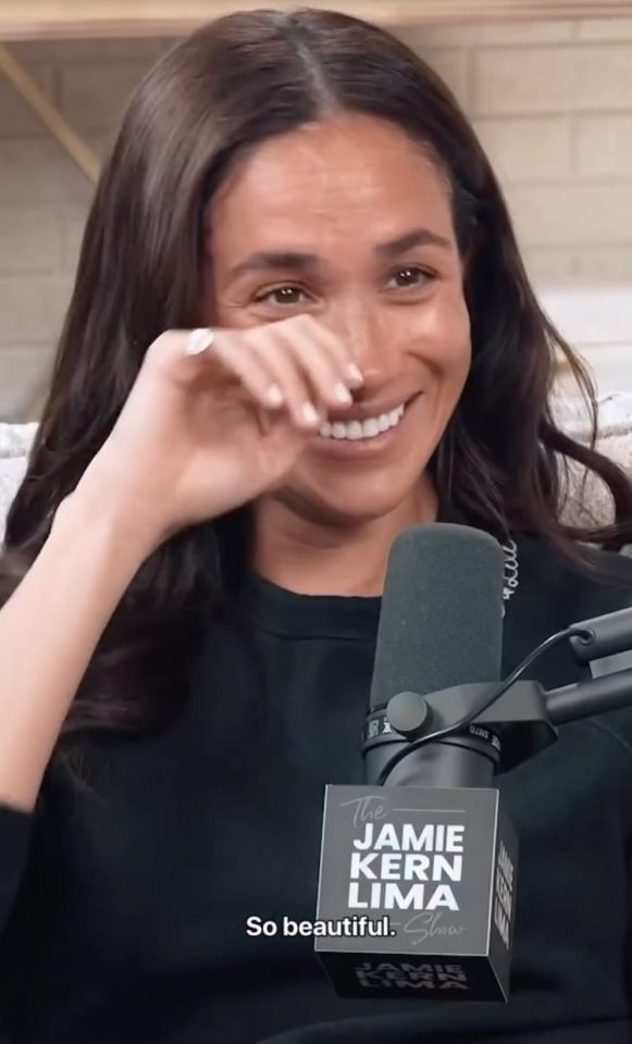Meghan Markle wiping away tears while smiling.