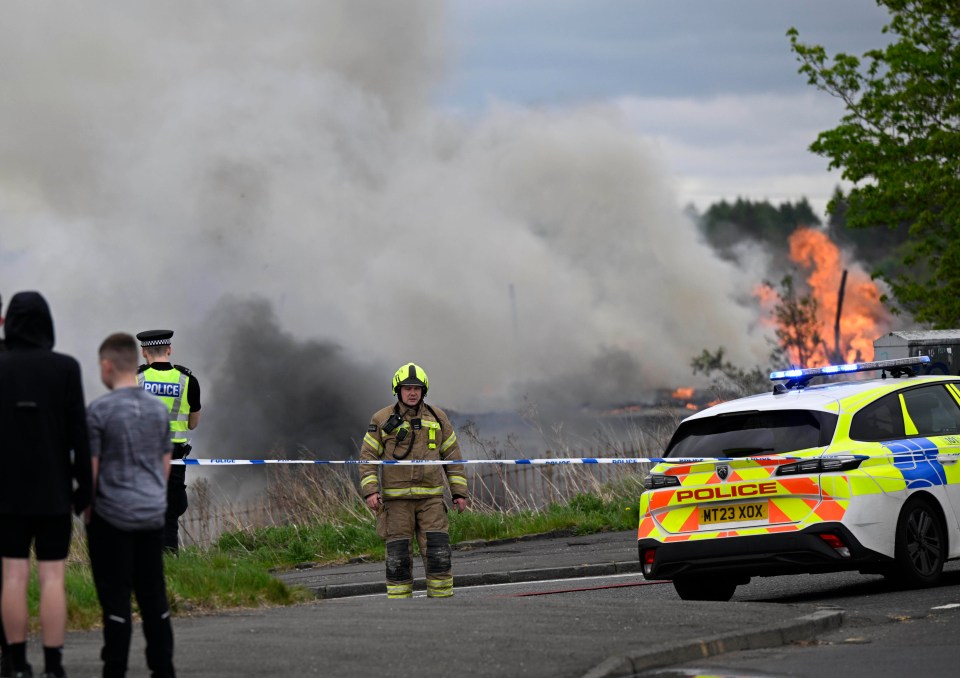 Firefighters and police officers at the scene of a large fire.