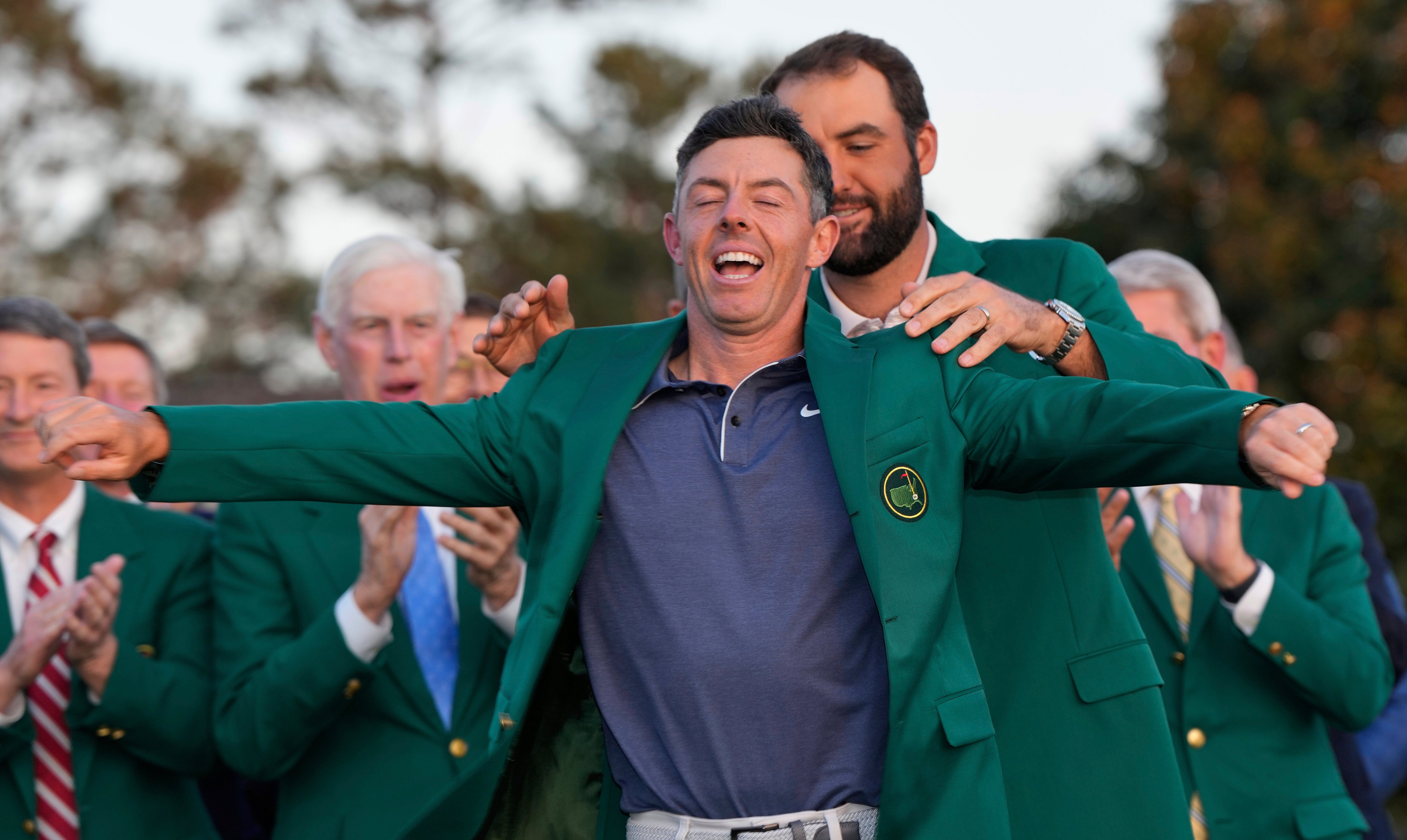 Scottie Scheffler putting the green jacket on Rory McIlroy at the Masters Tournament.