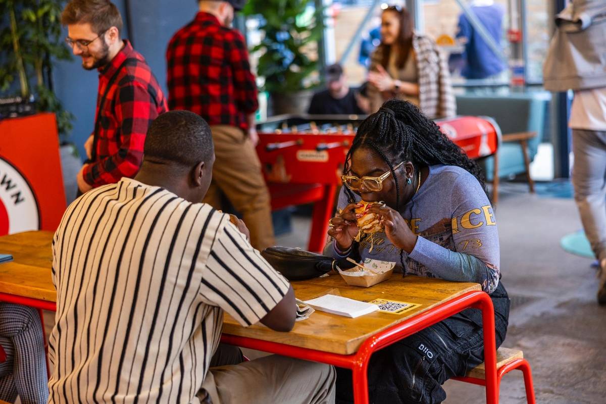 people sat at a table digging into huge sandwiches