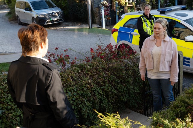 Tracy looks shocked as the police arrive at her door
