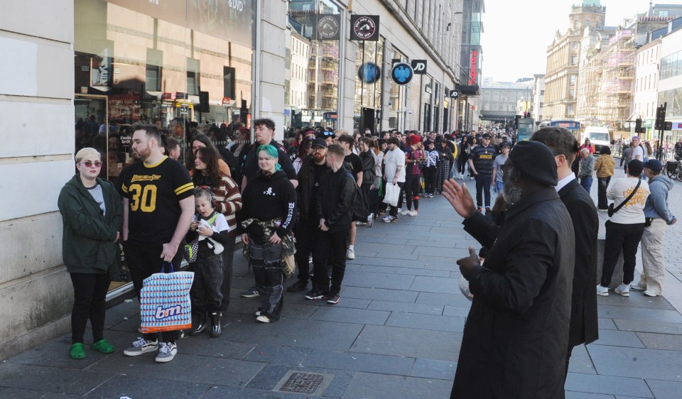 A long line of people waiting outside stores.