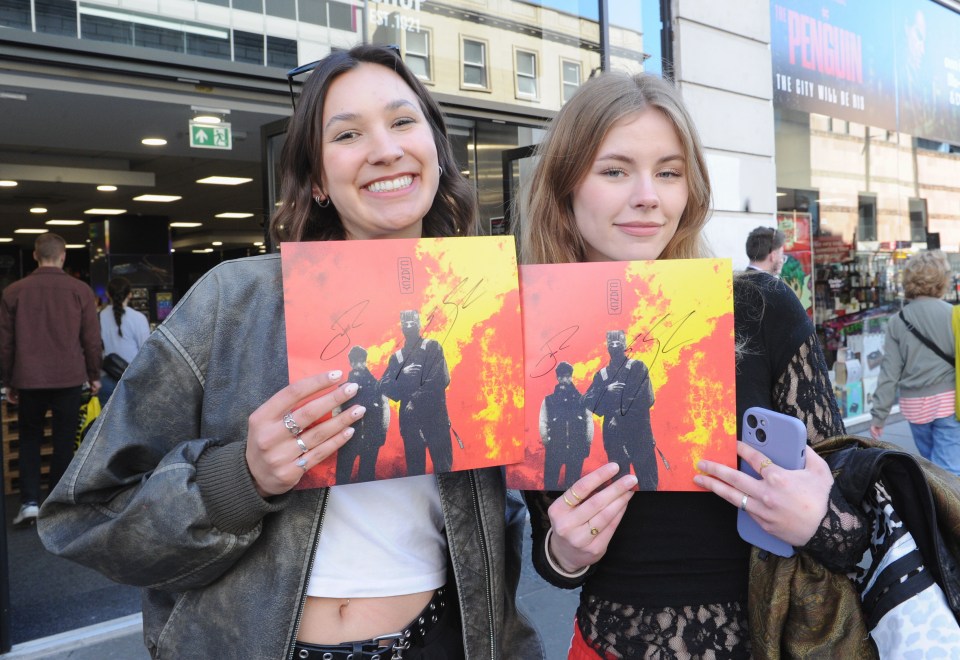 Two fans holding autographed 21 Pilots albums.