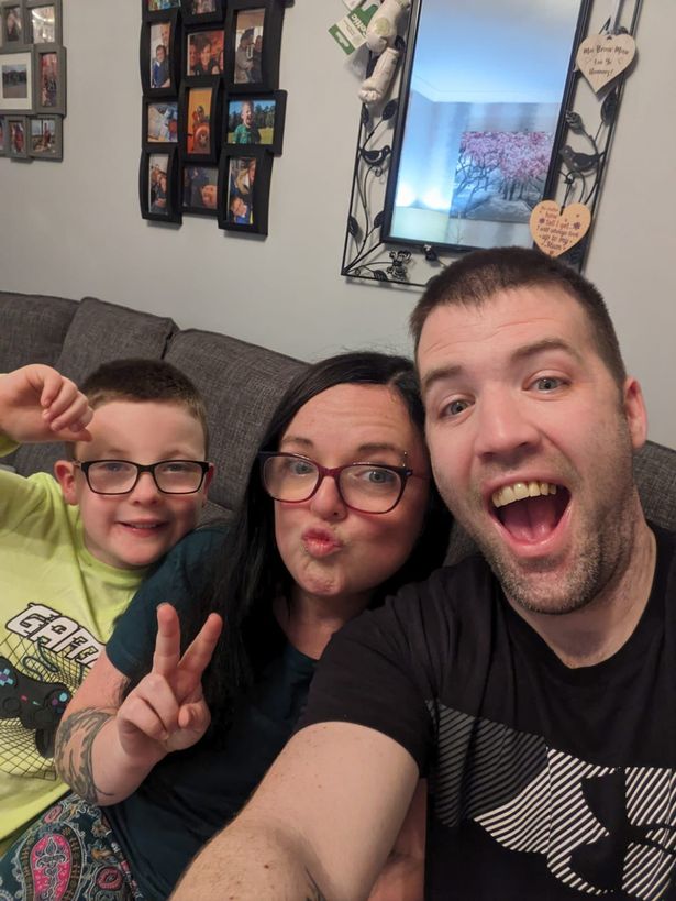An image of a young boy wearing glasses, a dark-haired woman with glasses, and a short-haired man posing for a selfie.