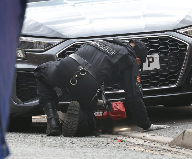 An officer examines a car after a double stabbing in Cobden Street, Pendlton, Salford 