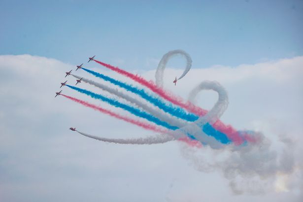 Eight planes in the sky leaving red, white and blue smoke trails