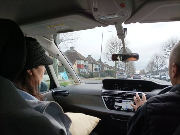 A photo of Anna and another person sitting in the front seat of a car