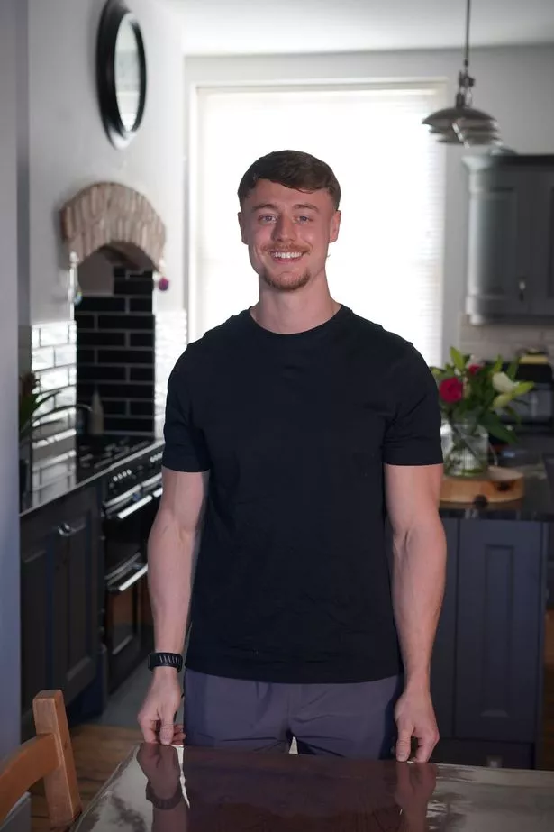 A young man in a black t-shirt standing in a kitchen
