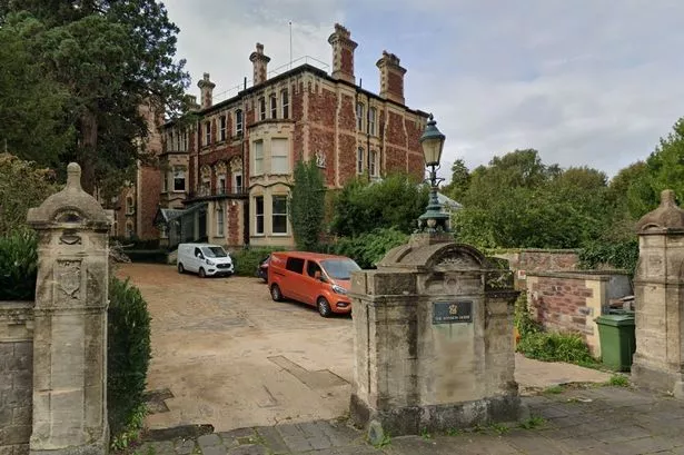 Large brick mansion behind a wide driveway