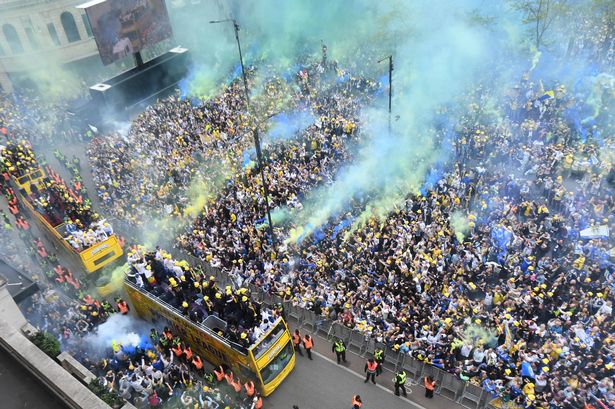 Leeds United players on the open top buses make their way through City Square