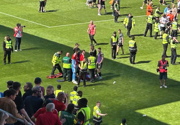 Aberdeen's Jack MacKenzie gets treatment on the pitch as fans invade the pitch after Dundee United's victory over Aberdeen at Tannadice Park, Dundee. Picture date: Saturday May 17, 2025. PA Photo. See PA story SOCCER Dundee United. Photo credit should read: Ronnie Esplin/PA Wire.
