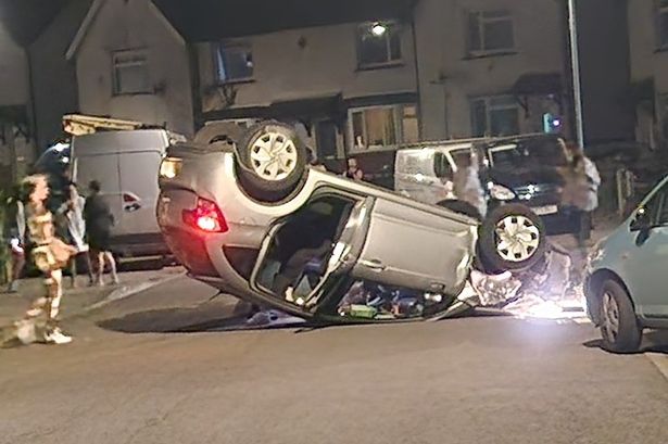 Silver Citroen flipped onto its roof in the middle of a residential street