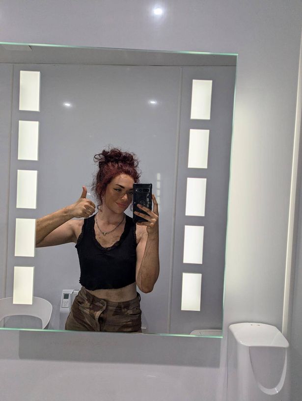 El taking a photo of herself in a bathroom mirror and holding a thumbs up