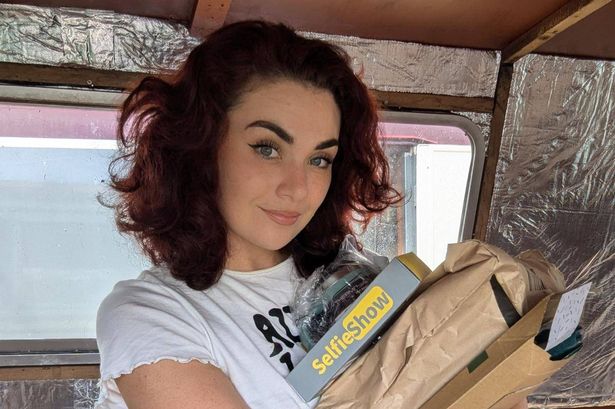 El standing inside her narrowboat and holding a bundle of parcels